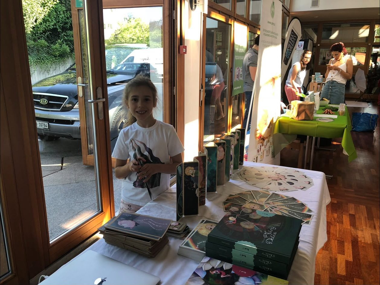 A young visitor at the Fairy Dalia stall, books and art postcards laid out on the table