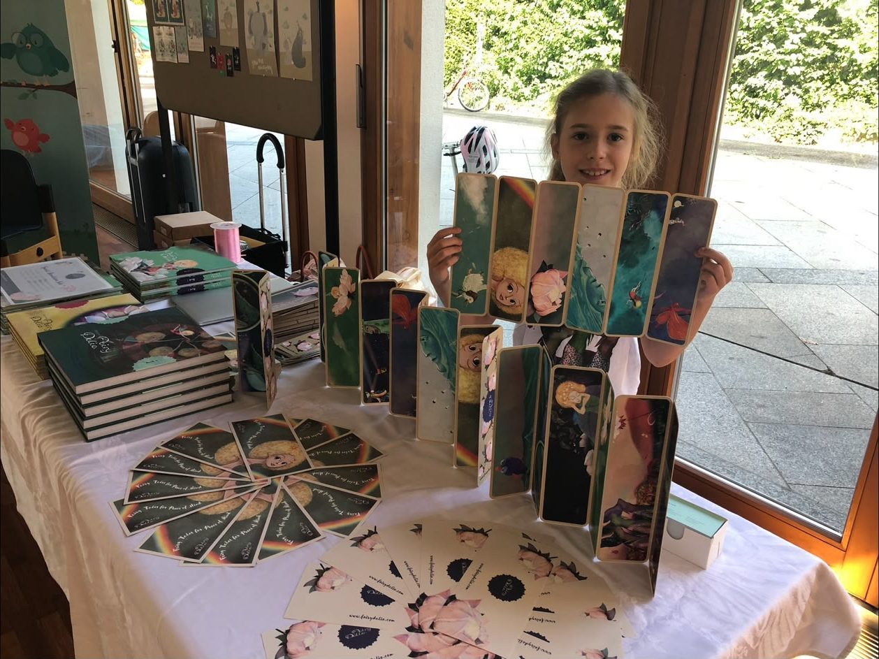 A girl holding up a row of Fairy Dalia bookmarks at the market stall