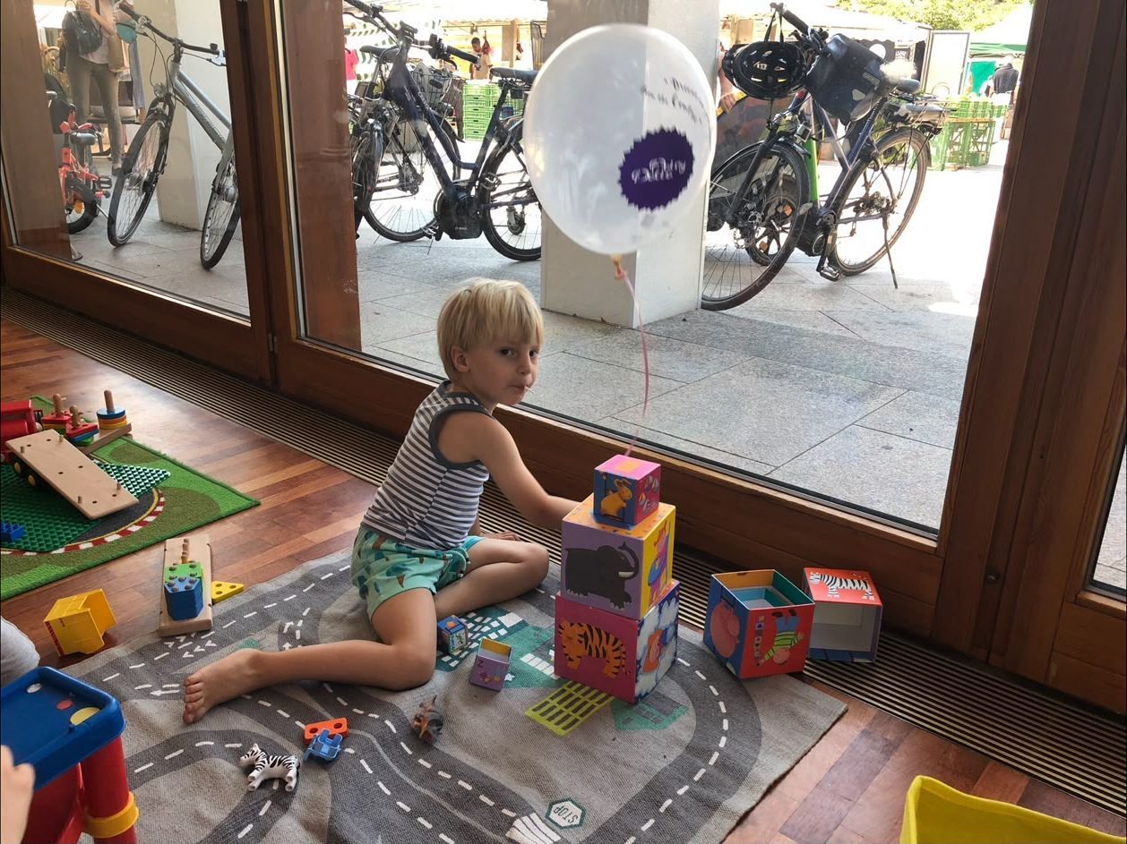 A small boy playing with wooden blocks beside a Mamalicious balloon